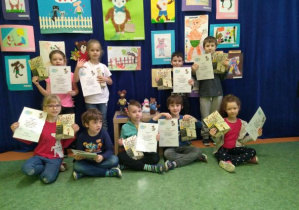 Dzieci z grupy Motylków pozują do zdjęcia z nagrodami za udział w konkursie na tle wystawy prac konkursowych